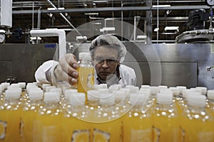 Quality control worker checking juice bottle on production line