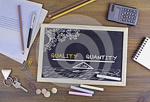 Quality Quantity Balance. Chalkboard on wooden office desk