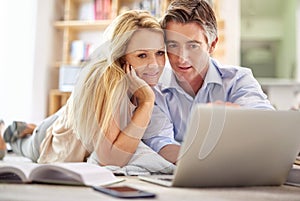 Quality time online. a mature couple lying on their living room floor doing some online research.
