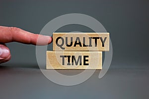 Quality time symbol. Wooden blocks with words `quality time`. Beautiful grey background. Businessman hand. Business and quality
