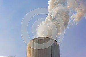 Qualmender Schornstein eines Kohlekraftwerks vor blauem himmel