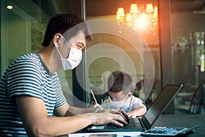 Quarantine asian man and children wearing protection mask working on computer at home while covid-19 virus inflected global photo