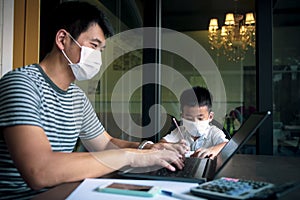 Quarantine asian man and children wearing protection mask working on computer at home while covid-19 virus inflected global photo