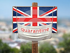 Quarantine during the COVID-19 coronavirus pandemic in Britain. Medical mask with the inscription Quarantine hangs on a sign with