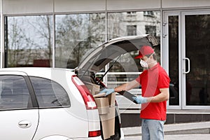 Quarantine and home delivery concept. Courier open trunk of car, takes out parcel