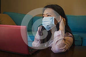 Quarantine and home lockdown - young beautiful worried and scared Asian Korean woman working or studying with laptop computer