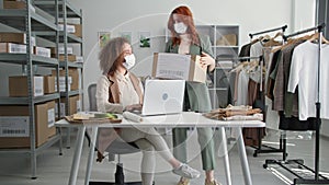 quarantine purchases, young female companions in medical masks work in online clothing store and arrange dispatches with