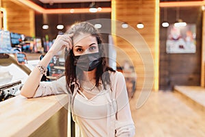 Quarantine rate in a cafe, a young woman in a black mask.