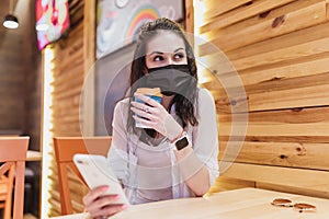 Quarantine rate in a cafe, a young woman in a black mask.