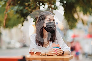 Quarantine rate in a cafe, a young woman in a black mask.