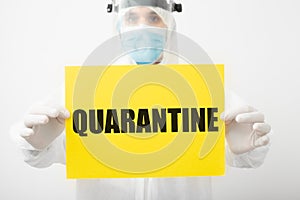 Quarantine, yellow warning sign with text Quarantine in doctor hands. Coronavirus covid-19 protection. Doctor in protective photo