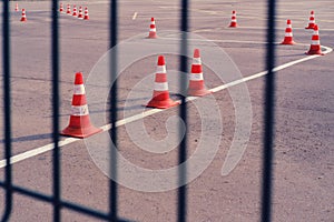 A quarantined coronavirus area for driving instruction. A fence with a grid and a school for training drivers with cones