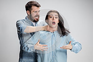 The quarrel men and women. Man strangling a woman on gray background