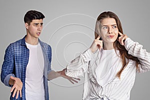 Quarrel and showdown. Sad woman covers her ears with fingers, upset man expresses negative emotions