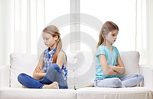 Quarreled little girls sitting on sofa at home