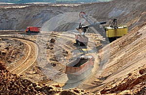 Quarry excavator loading sand or into dump truck at opencast