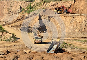 Quarry excavator and mining trucks transports sand in open pit. View of the quarry sand mine. Mining industry and construction