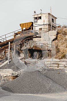 Quarry machines and piles of gravel over blue sky. Stone crushing and screening plant