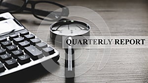 Quarterly report concept with glasses,magnifying glass and calculator on wooden background photo