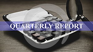 Quarterly report concept with magnifying glass and calculator on wooden background