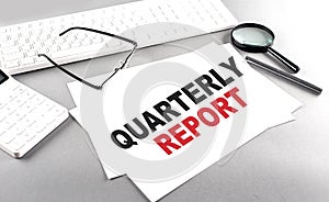 QUARTERLY REPORT text on a paper with keyboard, calculator on grey background photo