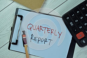 Quarterly Report write on a paperwork isolated on Wooden Table