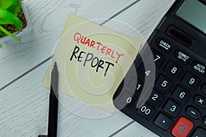 Quarterly Report write on sticky notes isolated on Wooden Table