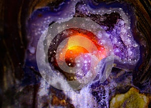 Quartz Crystal backlit to produce fiery glow, background abstract orange and purple