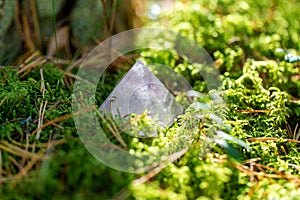 quartz crystal pyramid on moss in forest