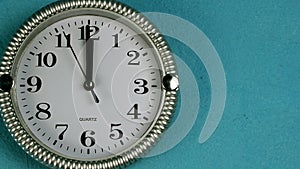 Quartz wall clock with second hand runs clockwise. The clock shows twelve oclock. On old blue wall. Close-up.