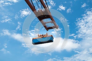 Quay crane discharging shipping container with blue sky background