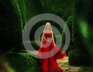 the queen in a red dress walks in the garden