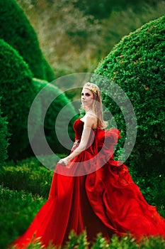 the queen in a red dress walks in the garden
