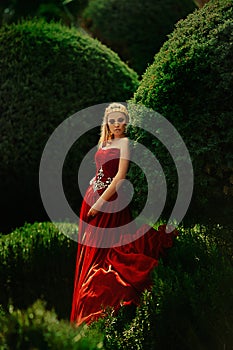 the queen in a red dress walks in the garden