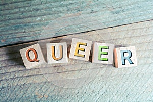 Queer In Colored Letters Written On Wooden Blocks On A Board photo