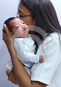 Quelling the cries of her baby. a young female nurse holding a baby who has a cleft palate.