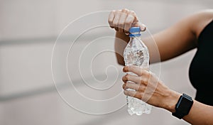 Quench thirst. African american young woman with smart watch opens water bottle