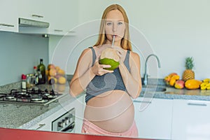 Quenching her pregnancy thirst with a refreshing choice, a pregnant woman joyfully drinks coconut water from a coconut