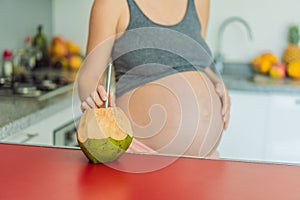 Quenching her pregnancy thirst with a refreshing choice, a pregnant woman joyfully drinks coconut water from a coconut