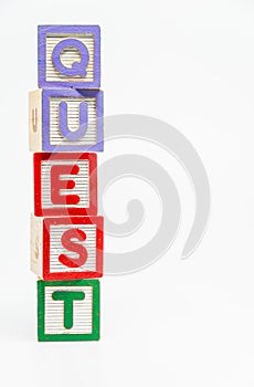 QUEST word wooden block arrange in vertical style on white background and selective focus