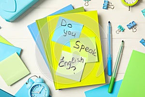 Question DO YOU SPEAK ENGLISH? and stationery on white wooden background, flat lay