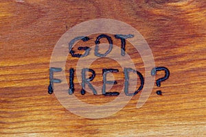 Question got fired handwritten with hand woodburner on flat brown wood surface