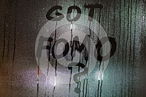 the question got FOMO - fear of missing out - handwritten on night wet window glass surface with bliurry street lights