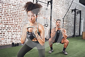 The question isnt can you, its will you. two sporty young people using kettlebells while working out at the gym.