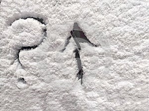 A question mark and arrow written in the snow. The cold frosty texture of the snow and the question mark. Background