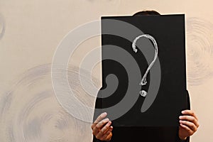 A question mark drawn on a black Board that covers a person`s face