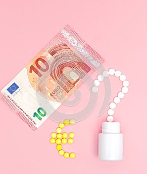 A question mark and euro mark laid out of pills and 10 euro on a pink background. Concept of medicine, money and health