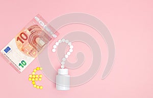 A question mark and euro mark laid out of pills and 10 euro on a pink background. Concept of medicine, money and health