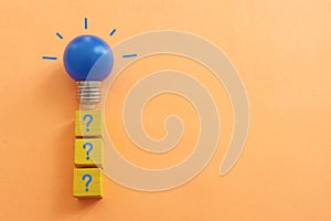 Question mark and light bulb over orange background, concept of idea, solution and creativity