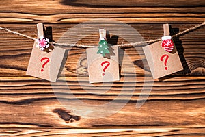 Question mark on little kraft paper stickers hanging on a rope on wooden clothespins. Santa Claus.  Rustic Christmas decoration